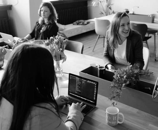 Women at desks coding on laptops