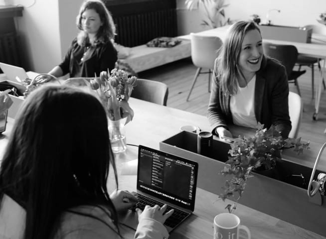 Women at desks coding on laptops